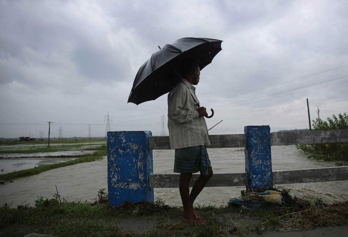 A farmer looks at the flowing river during a break from work. Hundreds of farmers have committed suicide or have died of starvation due to shut down of tea gardens. In 2014, as per the official figure