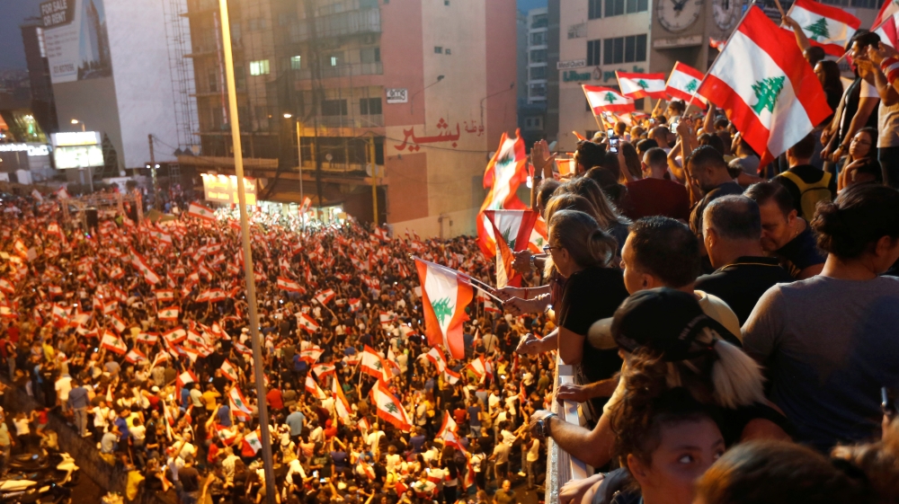 Demonstrators carry national flags as they stand on a bridge during an anti-government protest along a highway in Jal el-Dib