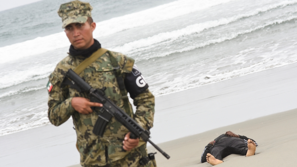A member of the Mexico''s National Guard keeps watch near the body of a migrant man from Cameroon washed ashore following a shipwreck in Puerto Arista