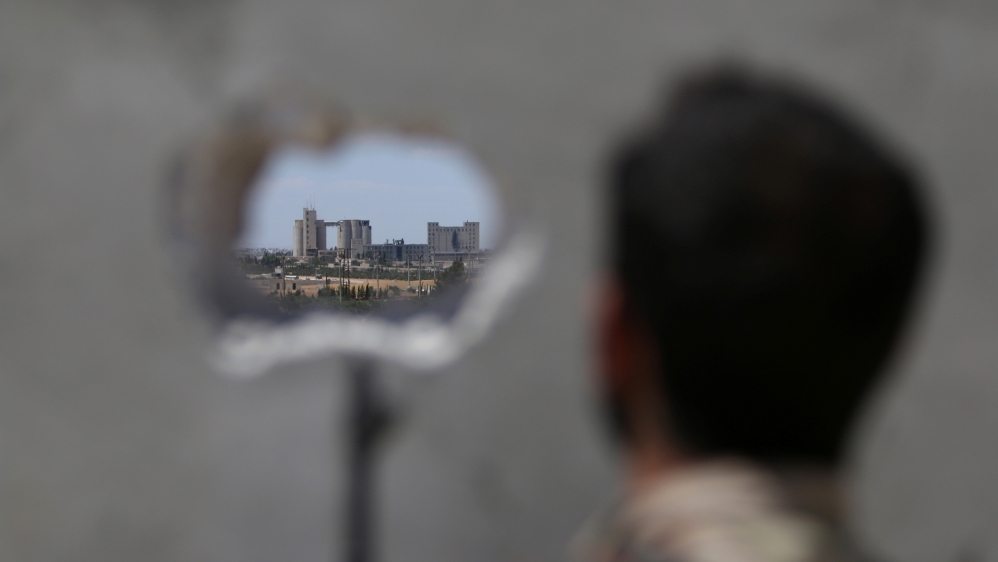 A Syria Democratic Forces fighter takes a position as he looks at Manbij's mills where Islamic State militants are positioned, in Aleppo Governorate, Syria June 16, 2016