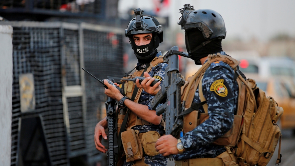 Members of Iraqi federal police are seen with military vehicles in a street in Baghdad