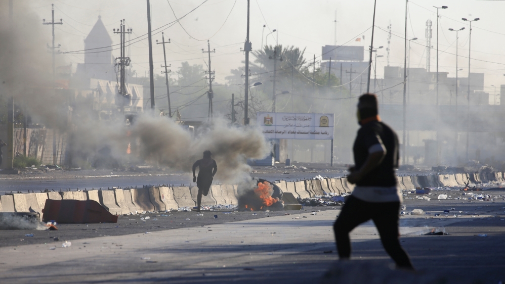 A man runs near burning objects at a protest during a curfew, three days after the nationwide anti-government protests turned violent, in Baghdad, Iraq October 4, 2019