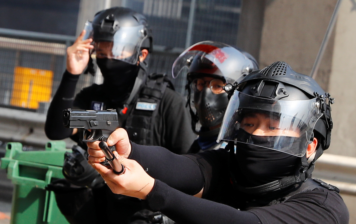 A riot police officer points a gun at protesters attempting to escape the campus of Hong Kong Polytechnic University (PolyU) during clashes with police in Hong Kong, China November 18, 2019. REUTERS/T
