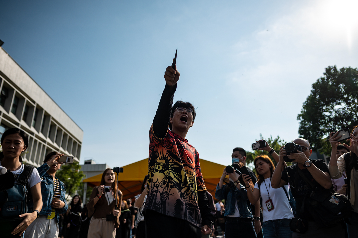 A mandarin speaking man points a knife at University students taking part in an anti-government protest during their graduation ceremony at the Chinese University of Hong Kong on November 7, 2019. - H