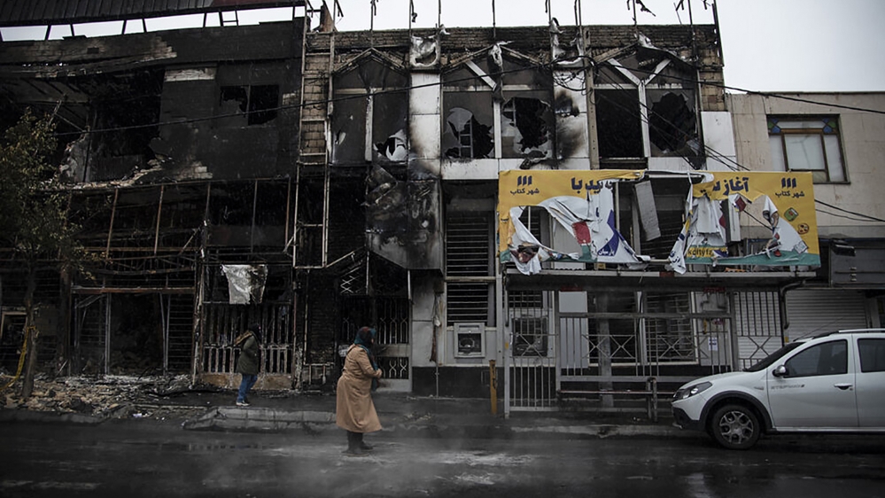 People walk past buildings which burned during protests that followed the authorities'' decision to raise gasoline prices, in the city of Karaj, west of the capital Tehran, Iran. An article published T
