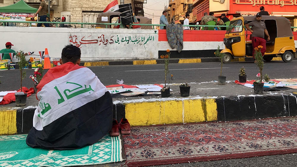 A young man reads the Quran in front of a memorial for the dead protesters  [Sofia Barbarani/Al Jazeera]