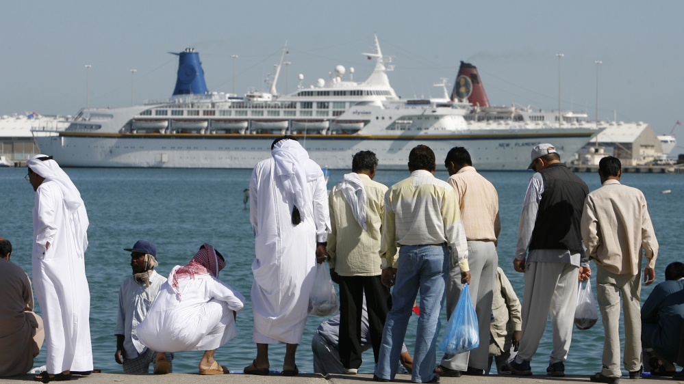 A cruise ship moors off the coast of central Doha behind men buying fish from local fishermen on the corniche 28 November 2006, three days before the 15th Asian Games open in the Qatari capital. With