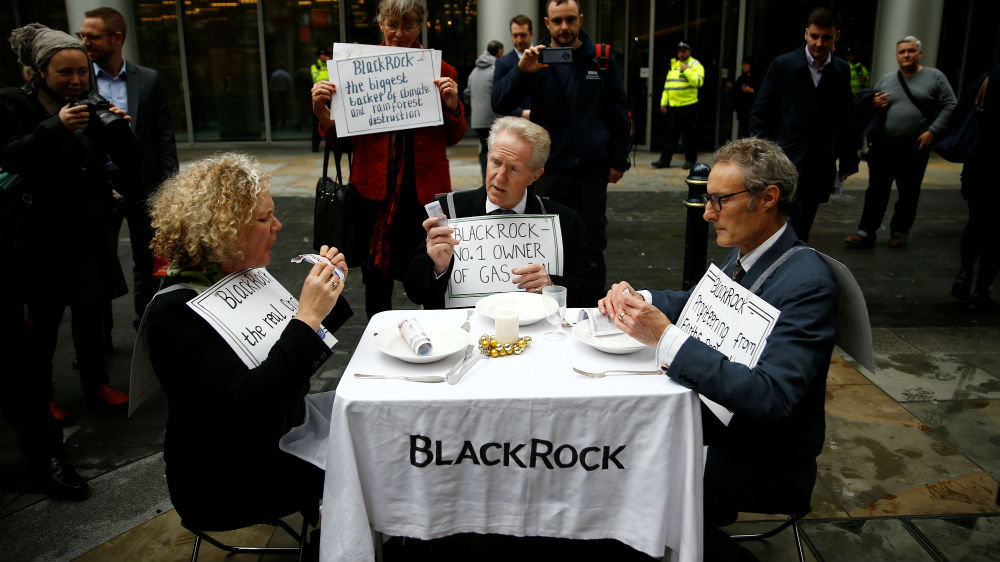 Protesters eat fake money outside the BlackRock office during an Extinction Rebellion demonstration in London