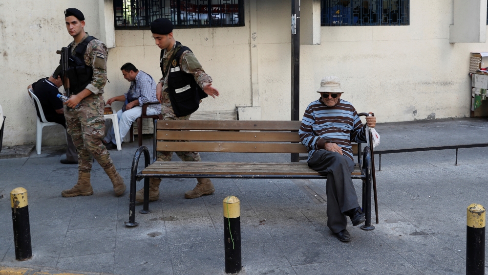 A man sits as Lebanese soldiers walk after they cleaned a road block set up by opposition supporters in Beirut, Lebanon, November 5, 2019. Picture taken November 5, 2019. REUTERS/Goran Tomasevic