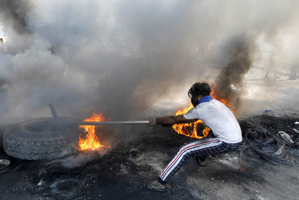 An Iraqi demonstrator pulls a burning tire as he blocks the road during ongoing anti-government protests, in Baghdad, Iraq November 3, 2019. REUTERS/Khalid al-Mousily