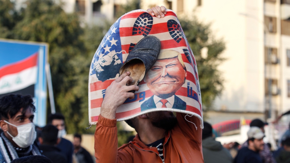 A protester places a shoe at a placard with U.S. President Donald Trump illustration outside the U.S. Embassy during a protest to condemn air strikes on bases belonging to Hashd al-Shaabi (paramilitar