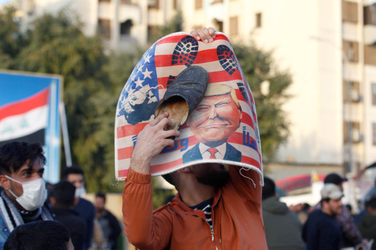 A protester places a shoe at a placard with U.S. President Donald Trump illustration outside the U.S. Embassy during a protest to condemn air strikes on bases belonging to Hashd al-Shaabi (paramilitar