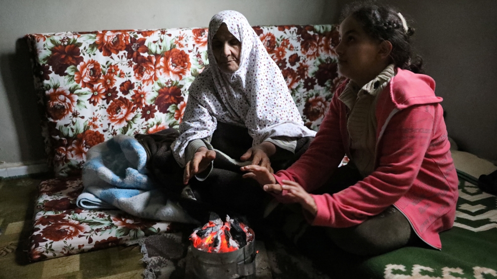A displaced family warm up their hands at an unfinished apartment in Tripoli