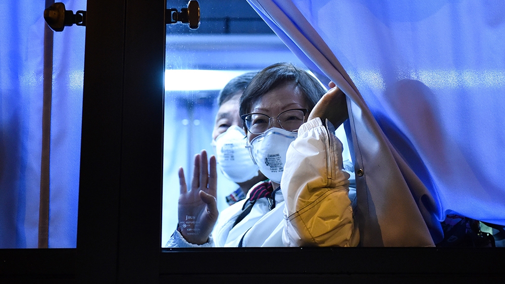 A US passenger waves to reporters while arriving at the Haneda Airport, in Tokyo on February 17, 2020 after disembarking in Yokohama from the Diamond Princess cruise ship, where people are quarantined