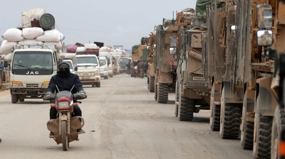 A man rides on a motorbike past Turkish military vehicles in Hazano near Idlib