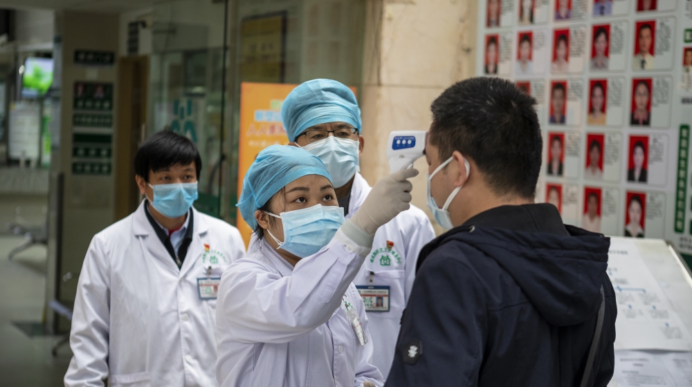 Medical personnel check the body temperature of people entering a community health center and pharmacy in Guangzhou, Guangdong Province, China, 03 February 2020. Wearing masks in metro and all public