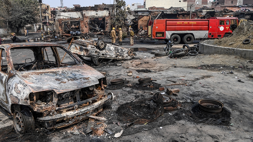 Firefighters stand near a fire rescue vehicle as they douse burnt-out tyre market premises following clashes between people supporting and opposing a contentious amendment to India''s citizenship law,