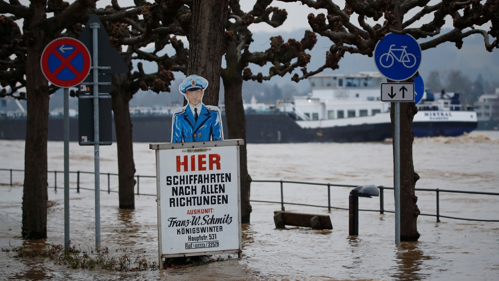 A sign for a cruising boat stands in the floods of the river Rhine as a freighter ship passes by in Koenigswinter