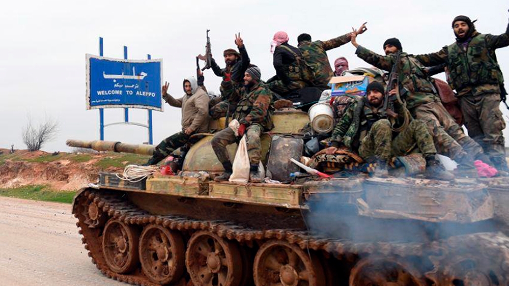 In this photo released Wednesday, Feb. 12, 2020, by the Syrian official news agency SANA, Syrian government soldiers on a tank hold up their rifles and flash victory signs, as they patrol the highway