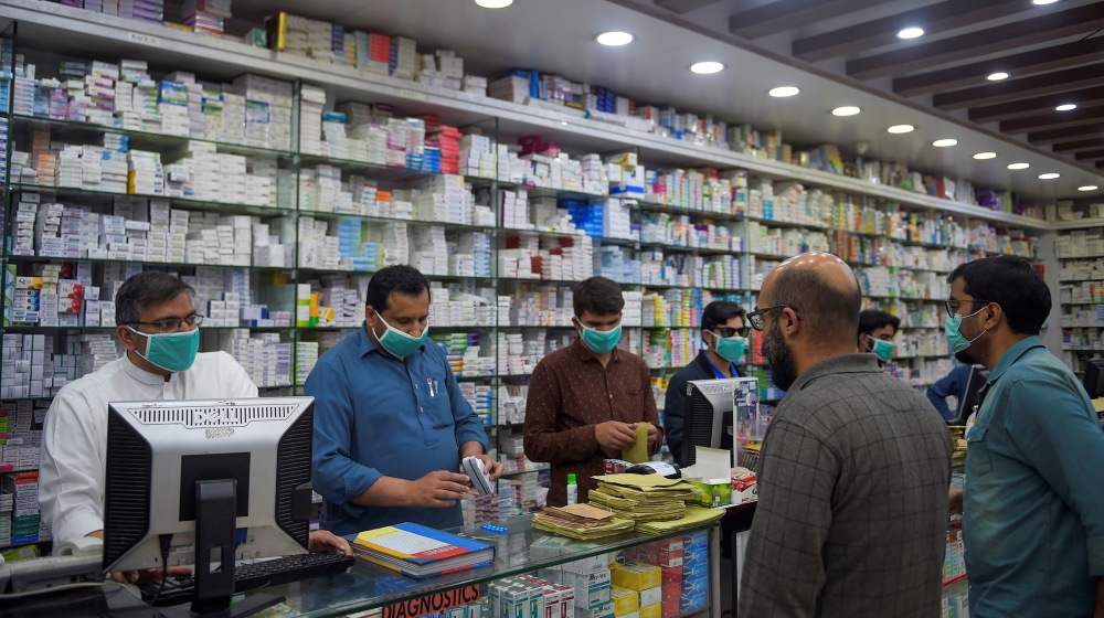 Pharmacy employees wearing facemasks as a preventive measure against the COVID-19 coronavirus attend to customers in Islamabad on March 23, 2020.  Farooq NAEEM / AFP