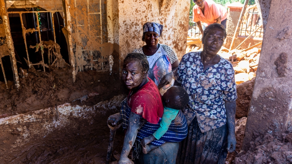 Women in Chimanimani’s Ngangu township scoop up mud from their home after mudfalls from Cyclone Idai swept through the hillside neighbourhood. [Tendai Marima/Al Jazeera]