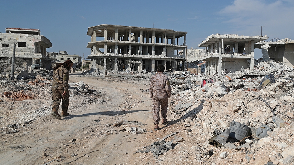 Rebel fighters walk amid rubble in the village of al-Nayrab, about 14 kilometres southeast of the city of Idlib in northwestern Syria, on March 7, 2020. (Photo by Omar HAJ KADOUR / AFP)