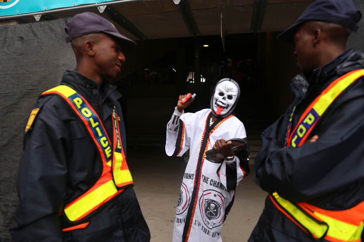 Orlando Pirates fan gestures to the police as he gets to the stadium. Masks are used largely on this day to send coded messages to the opposing team. Photo Antony Kaminju