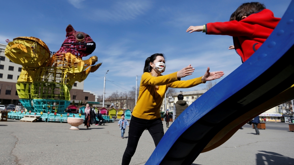 A woman wearing a protective face mask play with a child in Almaty