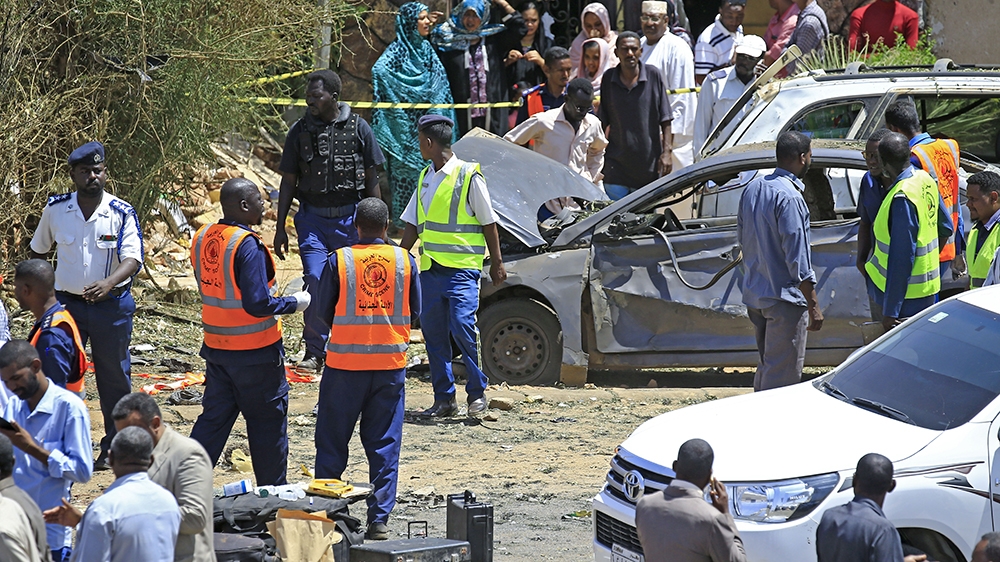 Sudanese rescue teams and security forces gather next to damaged vehicles at the site of an assassination attempt against Sudan's Prime Minister Abdalla Hamdok, who survived the attack with explosives