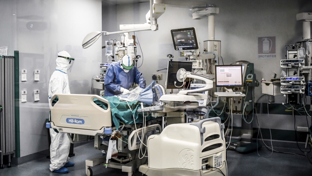 In this photograph taken from behind a window, doctors work on a Covid-19 patient in the intensive care unit of San Matteo Hospital, in Pavia, northern Italy, Thursday, March 26, 2020. The San Matteo