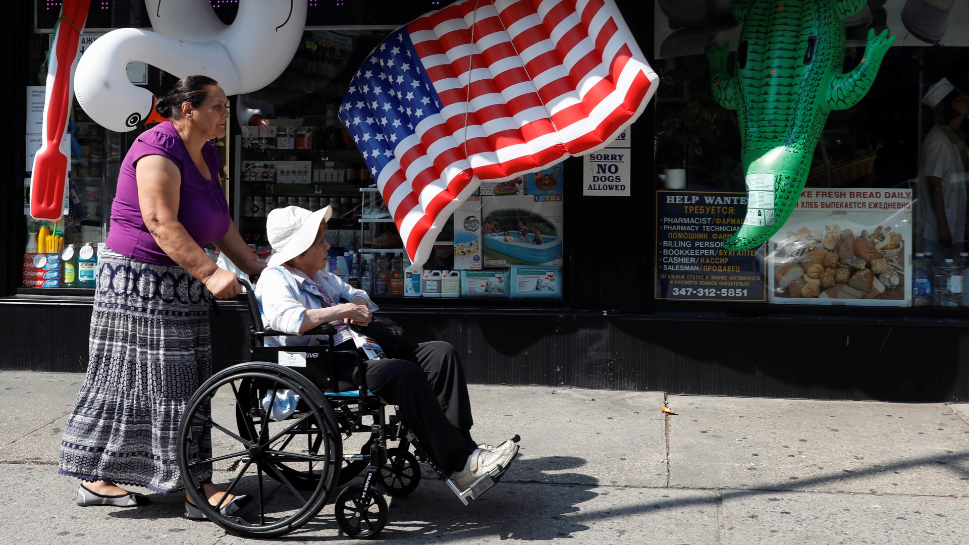 A woman is pushed in a wheelchair past a US flag inflatable raft in Brooklyn, New York