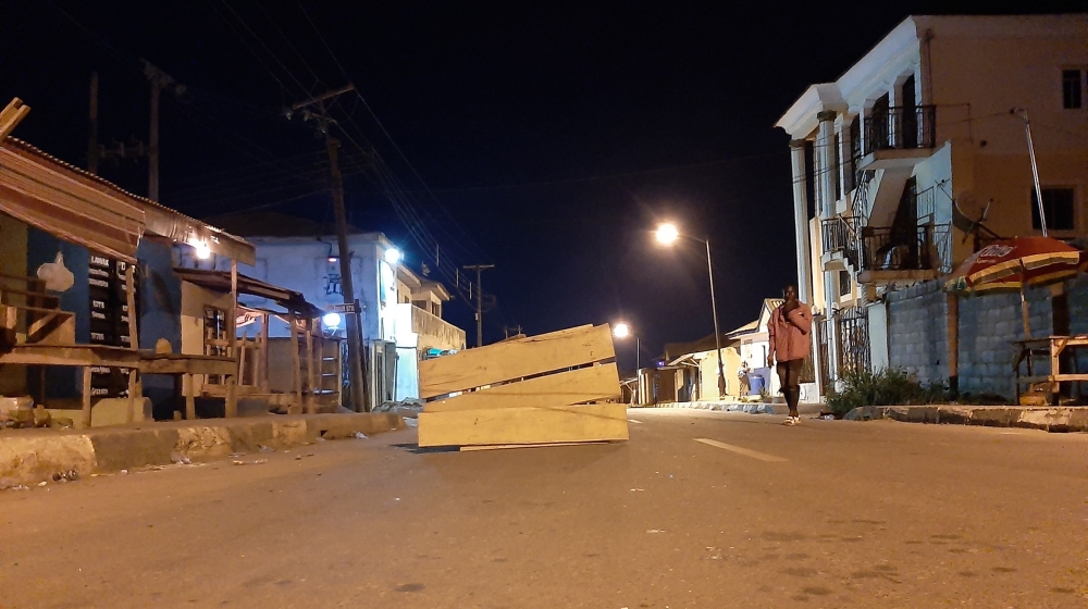 A vigilante member standing beside a street barricade in Lagos