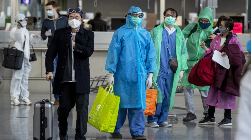 Chinese tourists walk to their gate to catch a flight to China at the airport in Frankfurt, Germany, Sunday, March 29, 2020. Due to the coronavirus only a few flights are leaving the airport these day