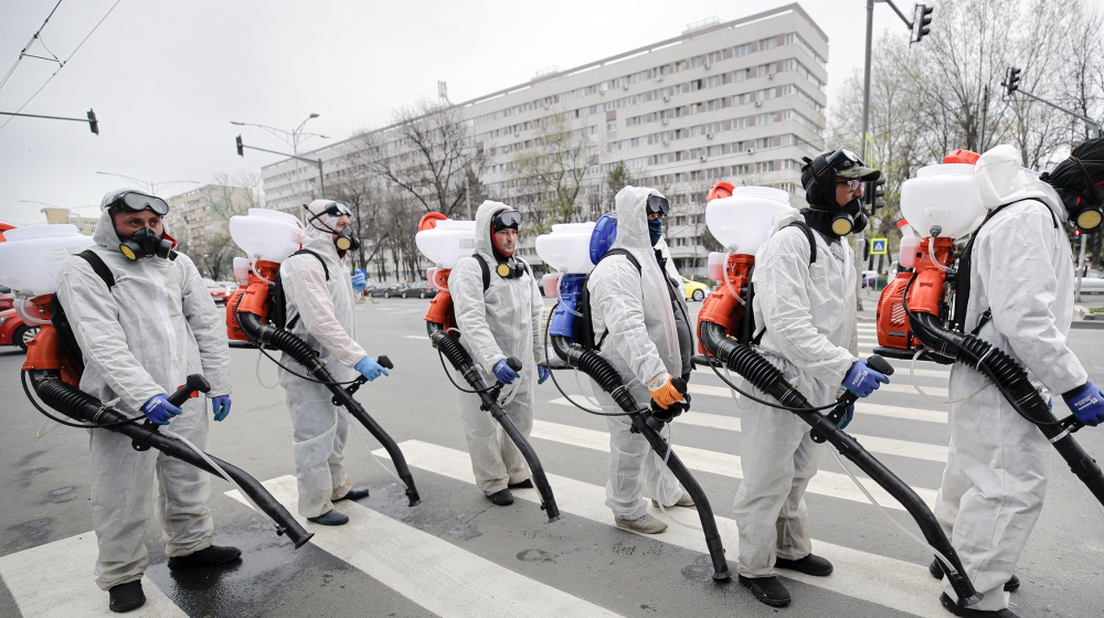 Municipal workers wearing protective outfits wait to reload the tanks with chemicals while disinfecting an area of the Romanian capital Bucharest, Romania, Tuesday, March 31, 2020 as authorities attem