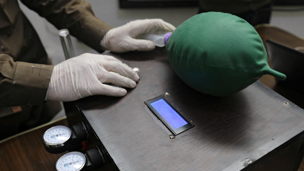 A volunteer wearing gloves builds a prototype ventilator