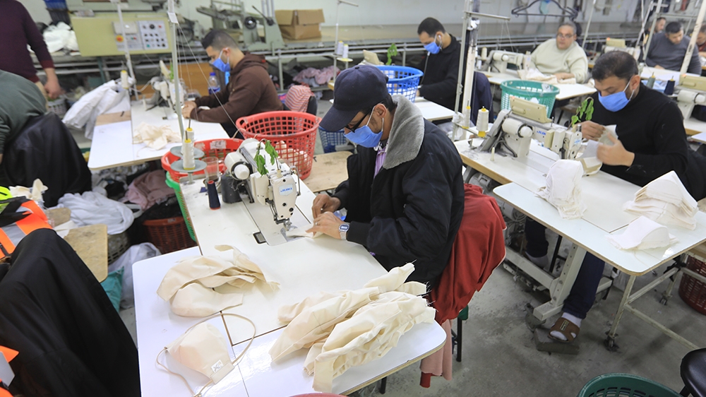 Palestinian workers sew medical clothing and protective masks at a factory east of Gaza city, on March 25, 2020, amid the COVID-19 epidemic. - The Queen Tex factory in the Gaza Strip used to specialis