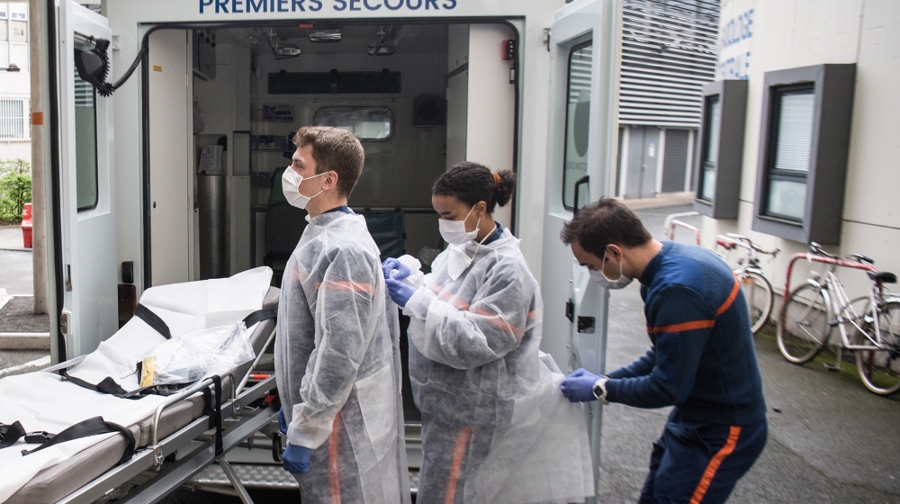 Health care members of French Civil Protection ("Protection Civile") dress prior to taking care of a migrant infected with coronavirus and carrying him to a cottage of a holyday center used as a cente