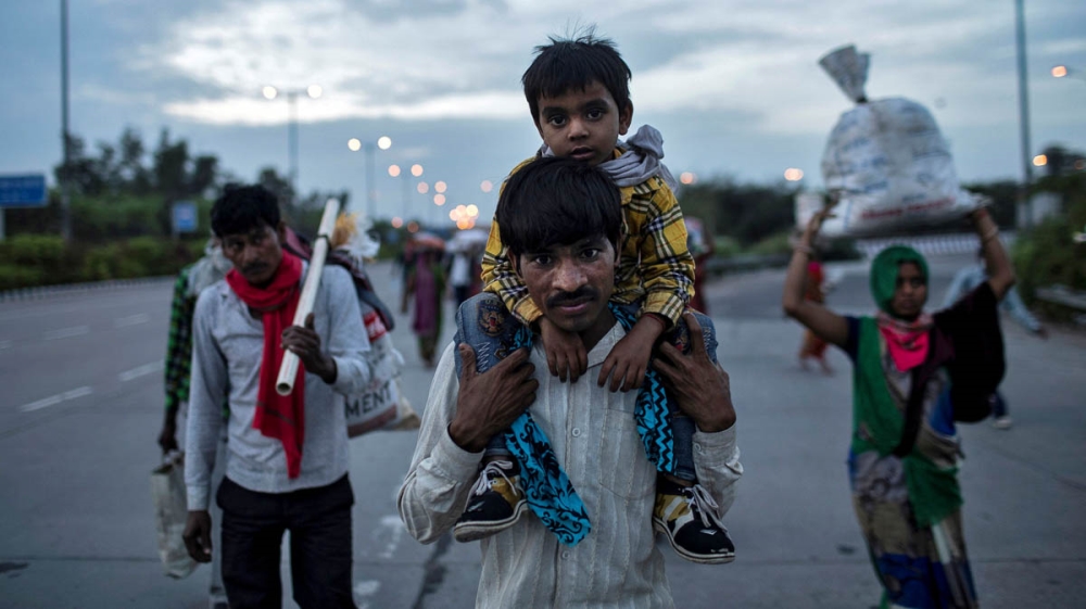 Dayaram Kushwaha, a migrant worker, carries his 5-year-old son, Shivam, on his shoulders as they walk along a road to return to their village, during a 21-day nationwide lockdown to limit the spreadin