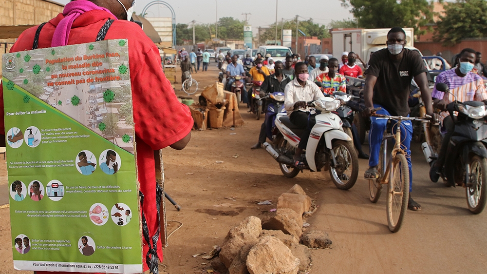 epa08331382 A man from Burkina Faso wears an information poster and uses a microphone on a roadside to deliver a public service announcement as part of an awareness campaign over the coronavirus SARS-