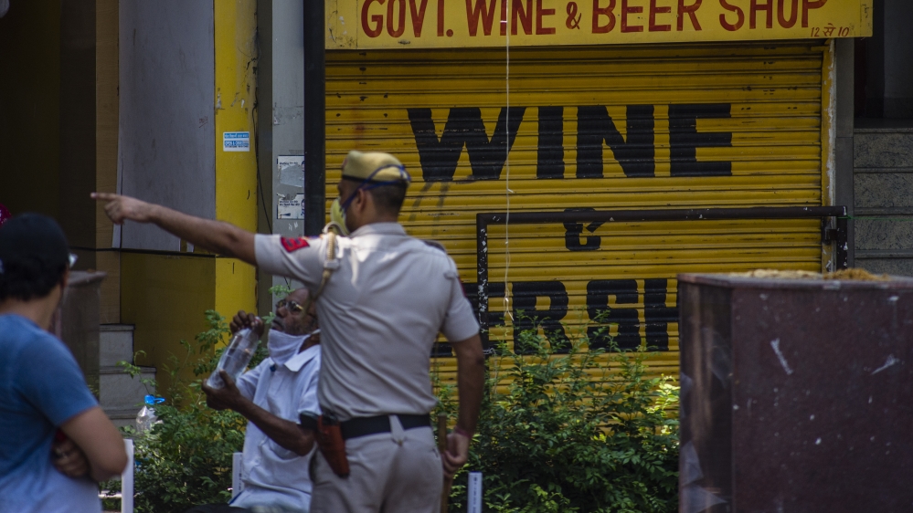 Indian policeman outside a liquor shop in New Delhi that had to be closed after large crowds gathered to buy alcohol