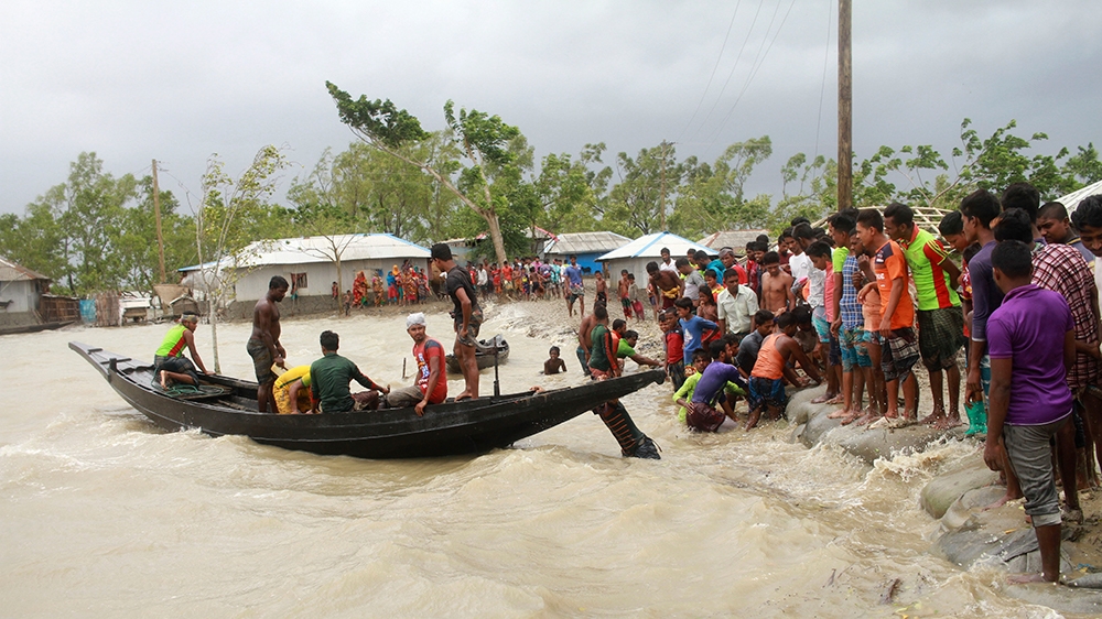 In this Wednesday, May 20, 2020 photo, people check an embankment before Cyclone Amphan made landfall, in Shyamnagar, Shatkhira, Bangladesh. A powerful cyclone that slammed into coastal India and Bang