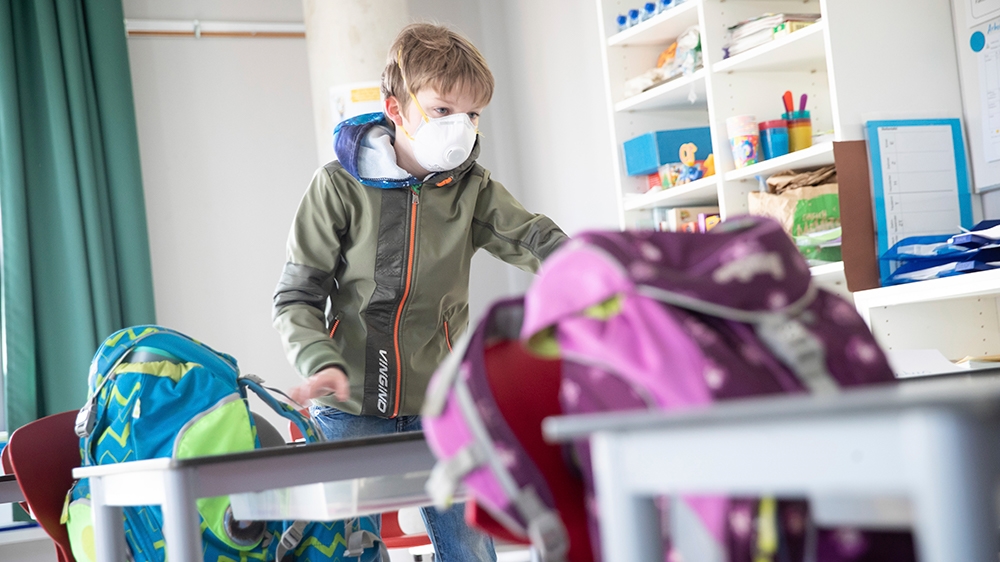 A student of class 4d comes into the class with a mouth guard and puts his satchel on his table at the Goldbeck School in Hamburg, Germany, Monday, May 4, 2020. On Monday, lessons began again for more