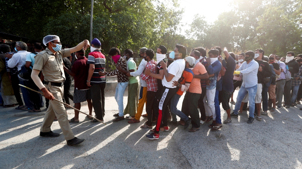 A police officer tries to control the crowds outside a wine store during an extended nationwide lockdown to slow down the spread of the coronavirus disease (COVID-19), in New Delhi, India, May 4, 2020