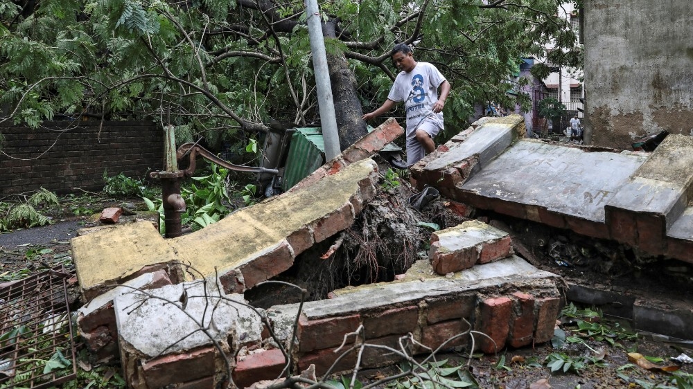 A man walks over a collapsed wall after Cyclone Amphan in Kolkata