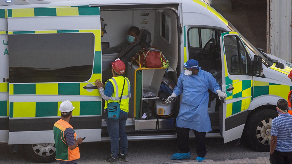 Emergency medical workers wearing protection equipment attend to a patient at a construction site in Doha, Qatar, April 05, 2020 [Sorin Furcoi/Al Jazeera]  