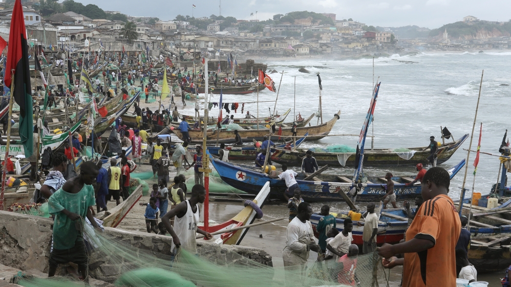 Fishermen tend their boats and fishing nets at Cape Coast