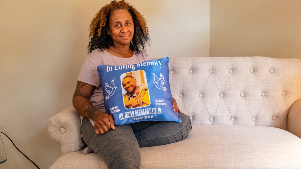 Jacqueline Sanders holds a pillow with a picture of her son, Oscar Cain, imprinted on it