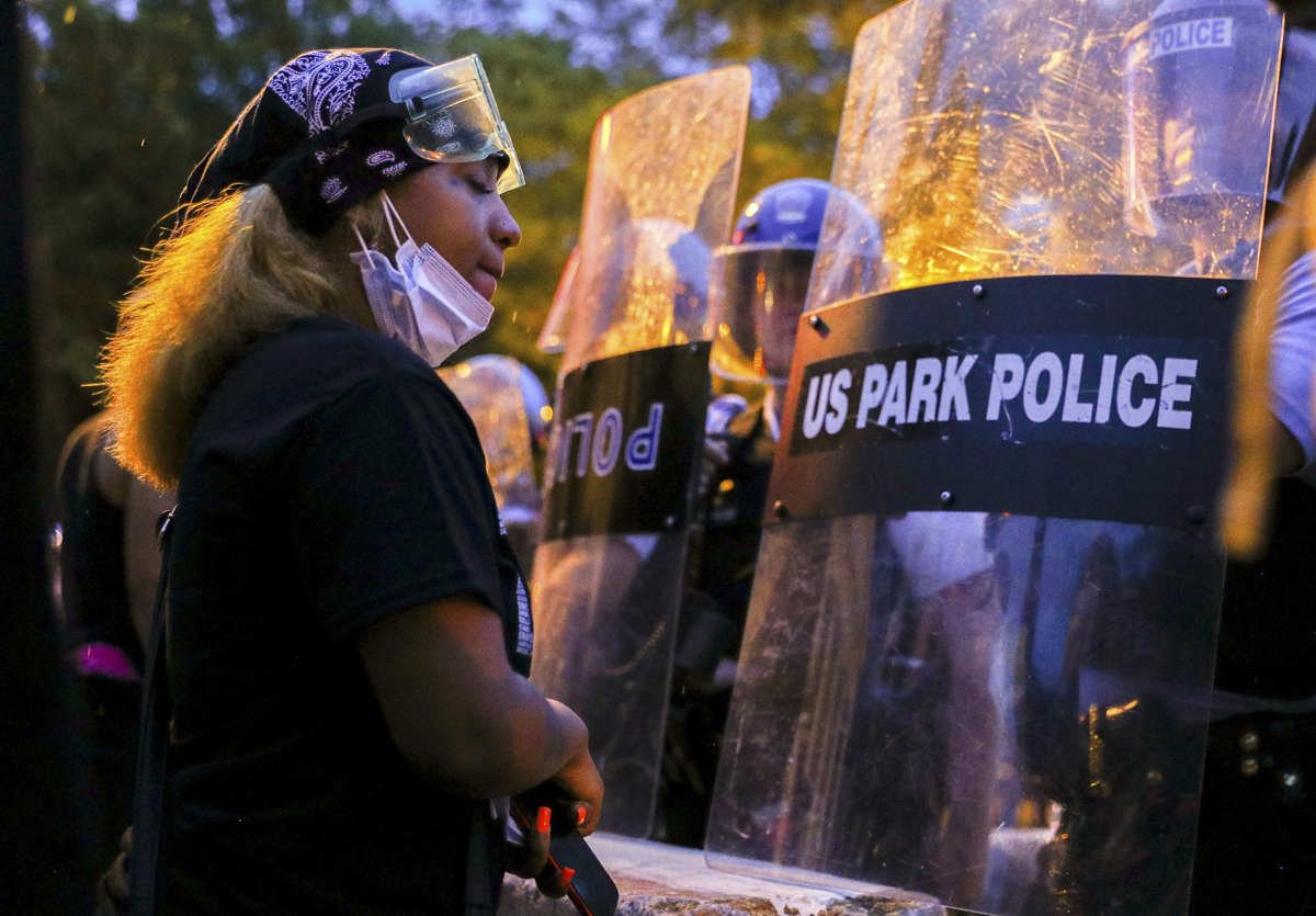 A protestor stands in front of a line of U.S. Park Police riot police as the two sides face off at Lafayette Park in front of the White House after police clashed with demonstrators trying to pull dow