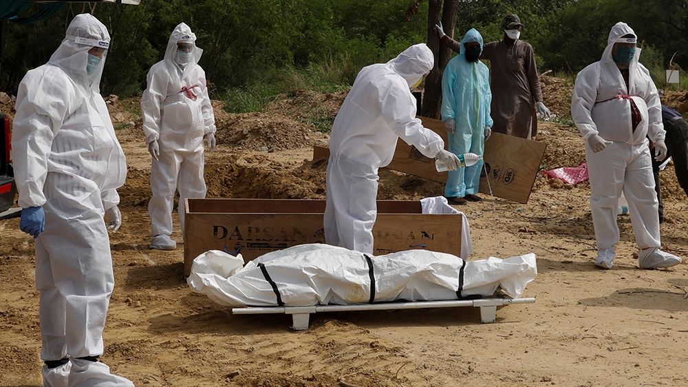Relatives wearing Personal Protective Equipment (PPE) perform the last rights to a person who died from the coronavirus disease (COVID-19), at a graveyard in New Delhi, India, June 27, 2020. REUTERS/A