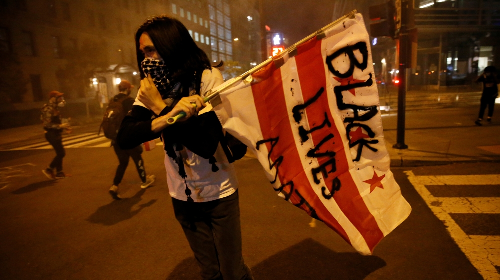 A man holds a flag as police disperse demonstrators during a protest amid nationwide unrest following the death in Minneapolis police custody of George Floyd, in Washington, U.S., May 31, 2020. REUTER